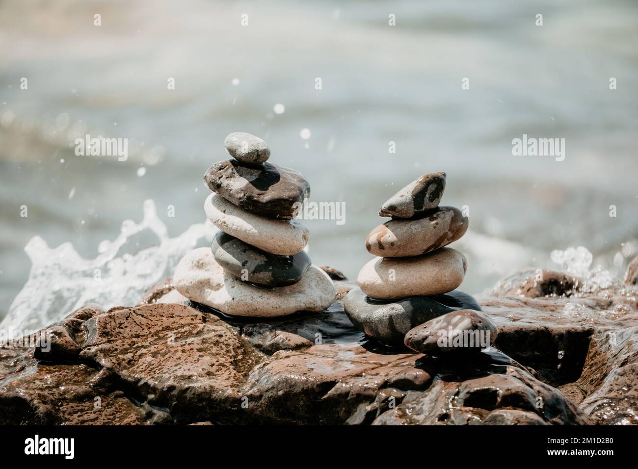 Piramide di roccia bilanciata sulla spiaggia di ciottoli, giorno di sole e cielo limpido al tramonto. Bokeh Golden Sea sullo sfondo. Fuoco selettivo, pietre zen sulla spiaggia di mare Foto Stock