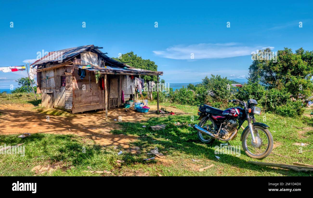 Provincia orientale di Mindoro, Filippine - 12 marzo 2022. Una casa di famiglia costruita con materiali recuperati, e una moto parcheggiata di fronte. Foto Stock