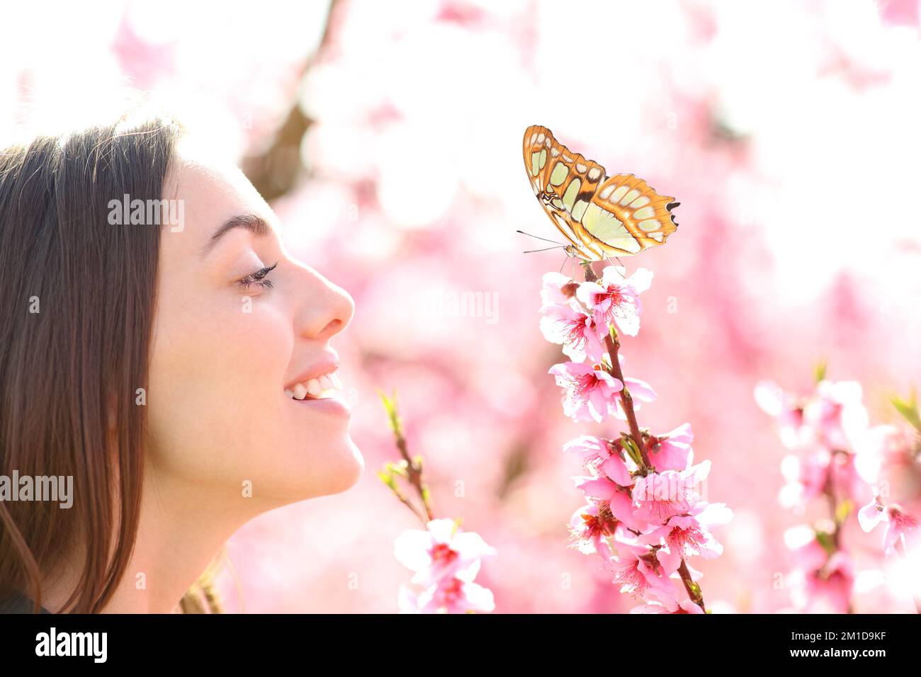Profilo di una donna felice lookijng a farfalla in un campo Foto Stock