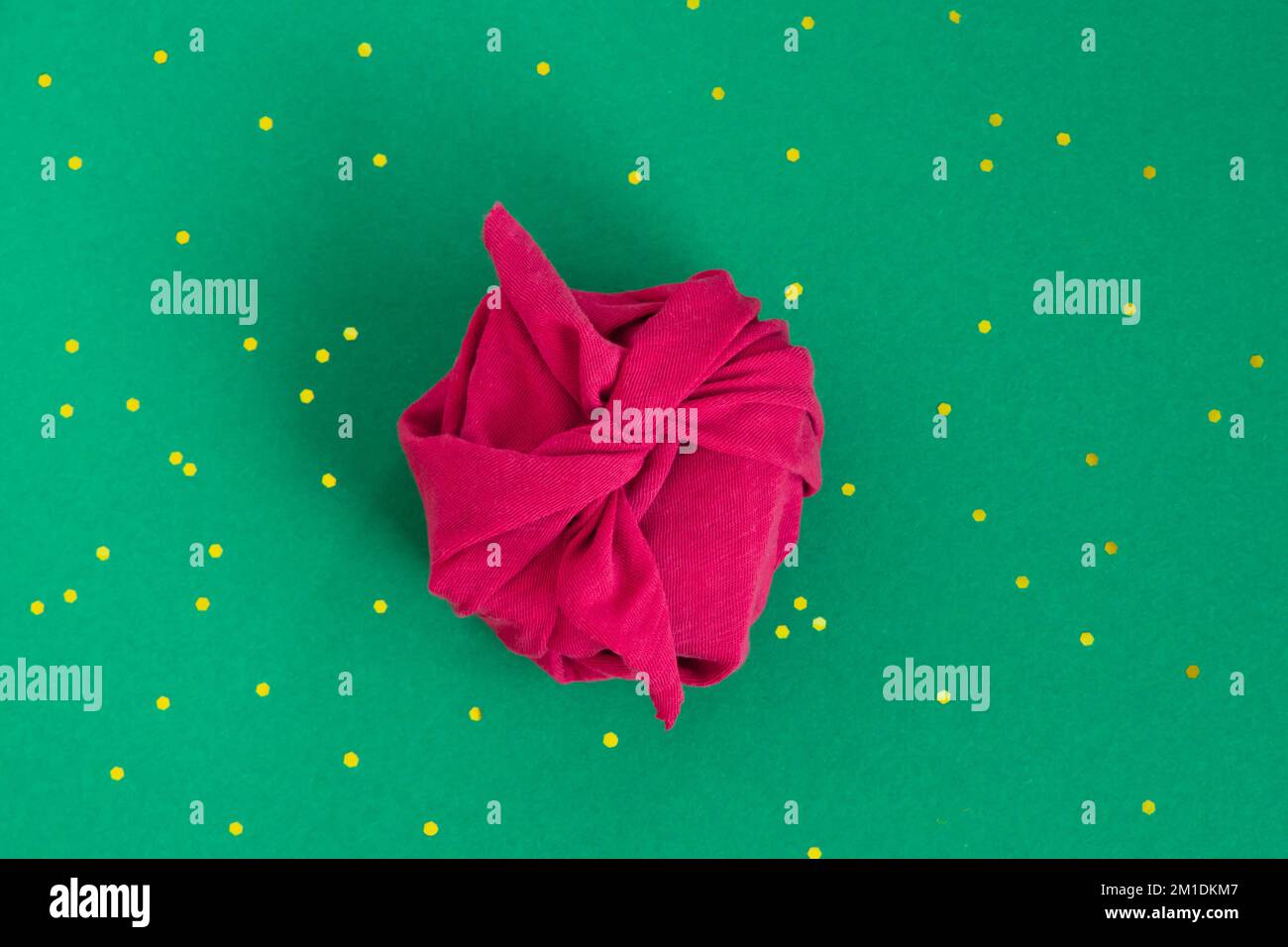 Carta regalo senza confezione tecnica Furoshiki. Tessuto Viva magenta su sfondo verde. Piano di giacitura, scatola di presentazione, vista dall'alto. Natale, San Valentino, nuovo Foto Stock