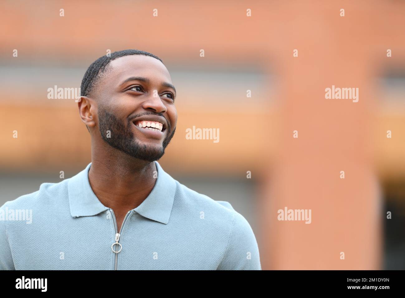 Felice uomo nero che guarda sopra a camminare per strada Foto Stock