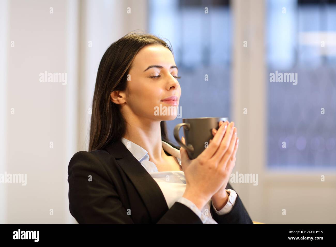 Donna d'affari rilassata bere caffè in ufficio Foto Stock