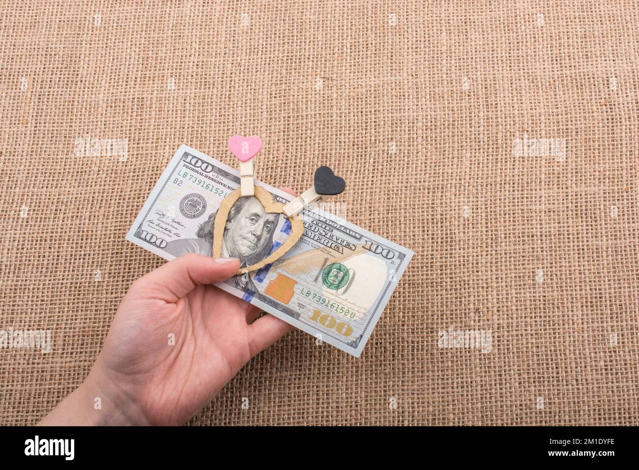 American 100 banconote di dollari con un clip di cuore in mano Foto Stock