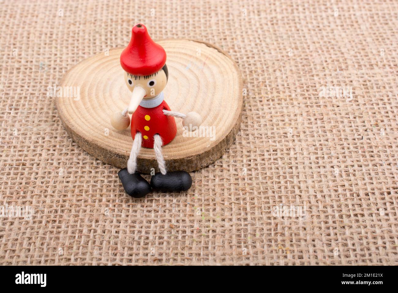 Pinocchio seduto su legno su sfondo di tela Foto Stock