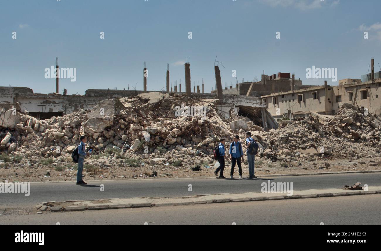Studenti che vanno a scuola in un quartiere distrutto di Bosra, Siria Foto Stock