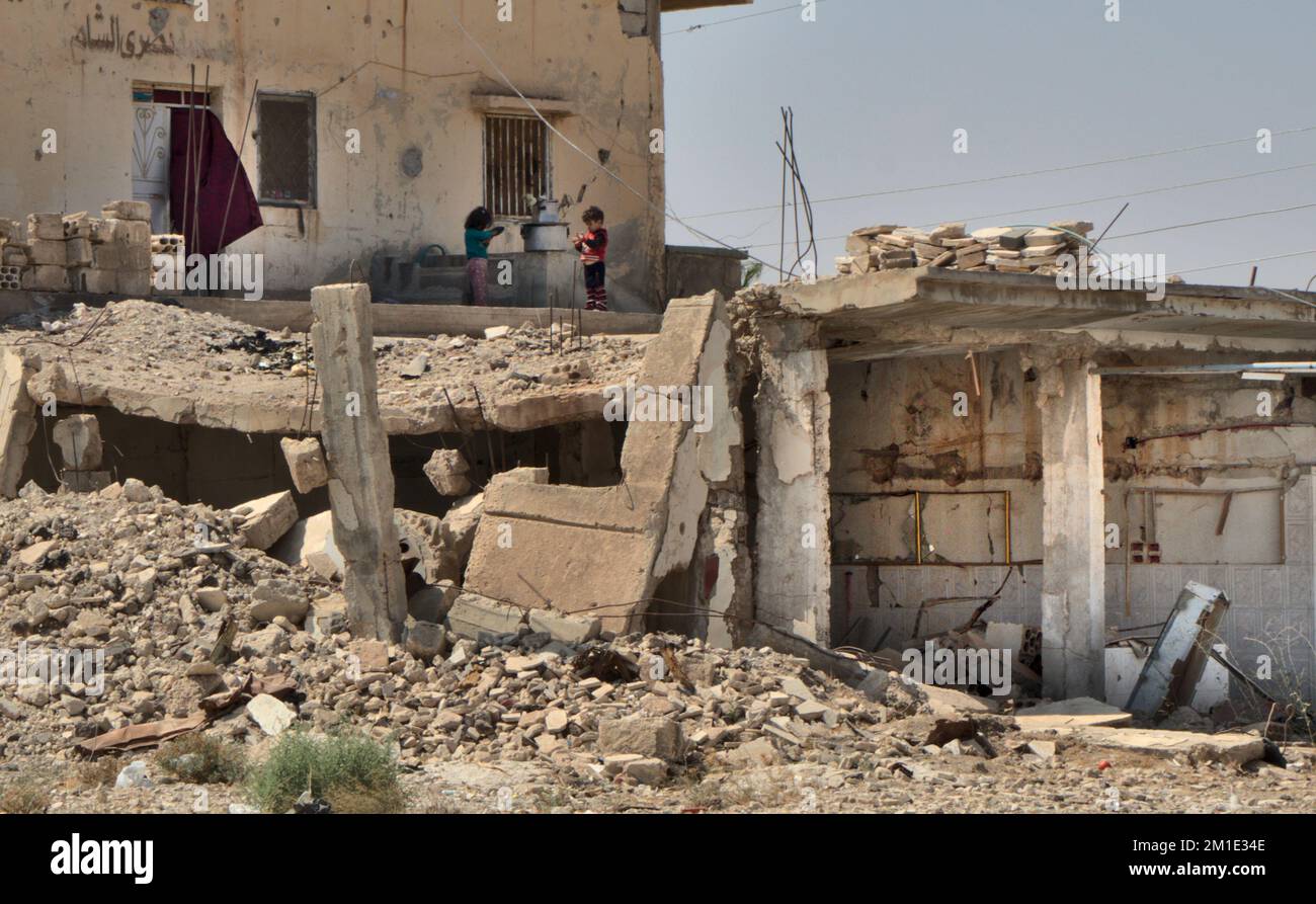 Due bambini giocano davanti alla loro casa danneggiata, Bosra, Siria Foto Stock