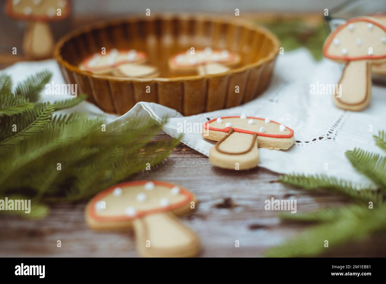 Primo piano di biscotti ai funghi di pan di zenzero su un tavolo di legno con rami di abete e una tovaglia in pizzo Foto Stock