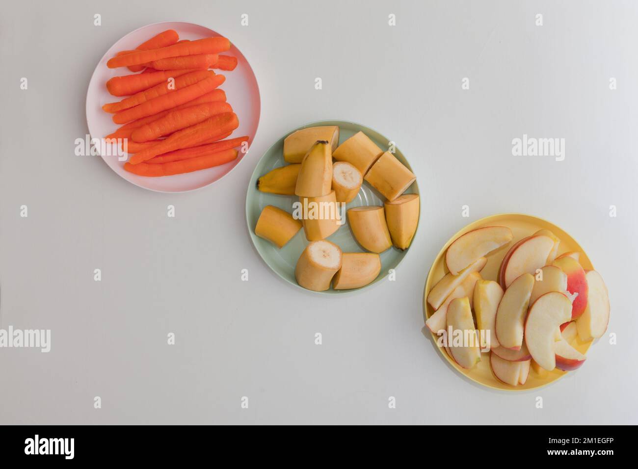 carota, mela e banana fette sui piatti, verdura fresca e frutta Foto Stock