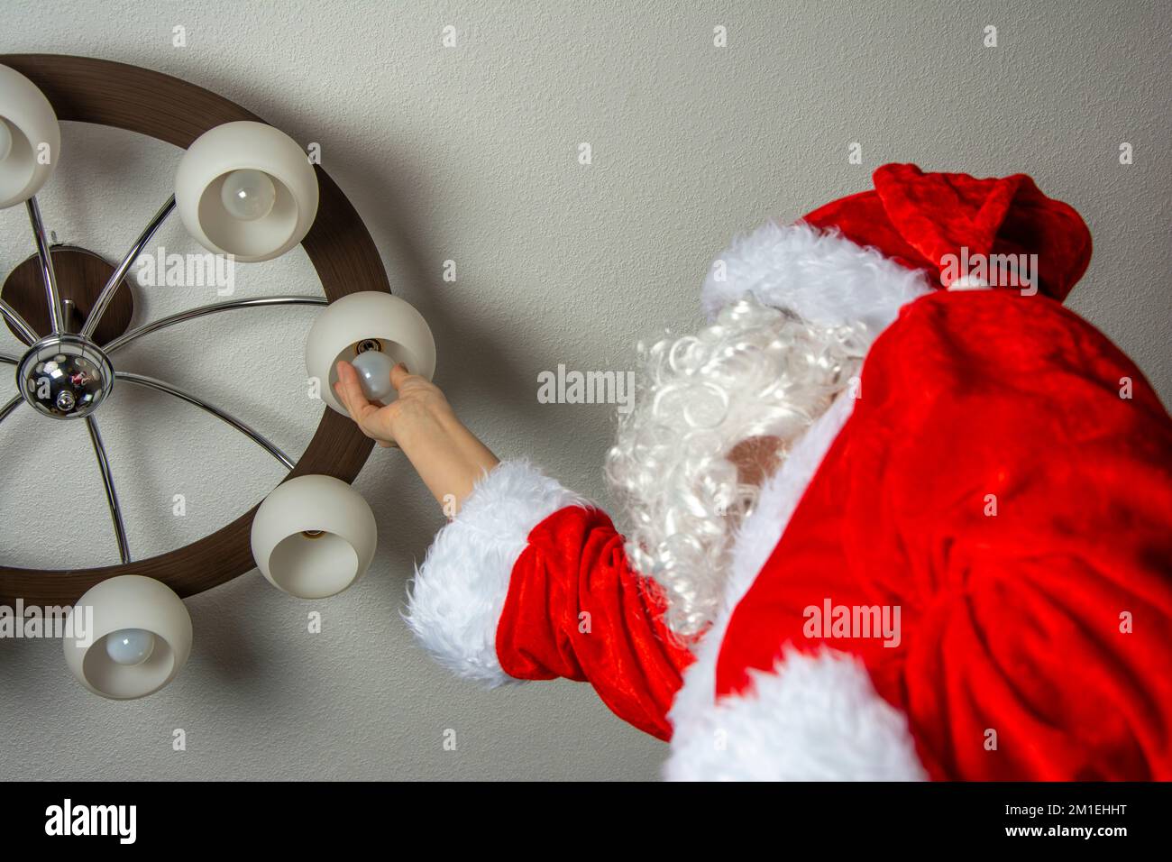 Babbo Natale cambia le lampadine bruciate nel lampadario Foto Stock