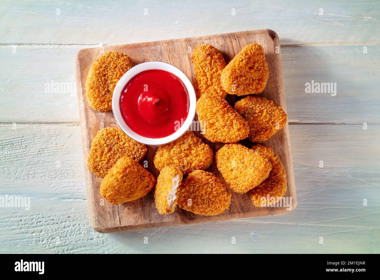 Bocconcini di pollo con ketchup su uno sfondo rustico di legno, top shot. Un antipasto croccante in un ristorante, un piatto fast food Foto Stock