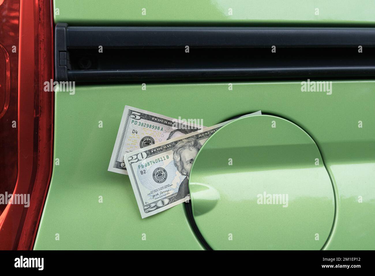 Banconote in un serbatoio di gas da un'automobile. Un aumento dei prezzi del carburante Foto Stock