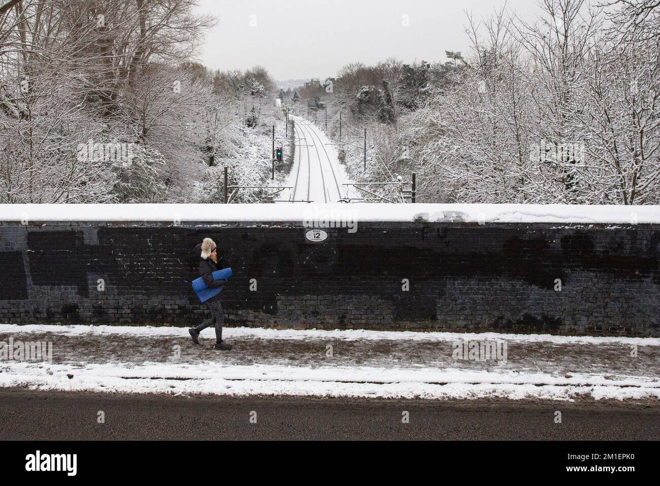 Londra, Regno Unito . Una persona cammina attraverso un ponte ferroviario pieno di neve a Queens Park, West London pendolari attraverso Londra affrontare una sfida. Foto Stock