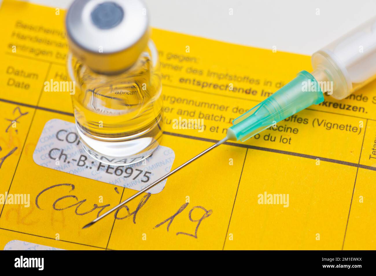 Primo piano del documento di vaccinazione giallo con siringa e flaconcino Foto Stock