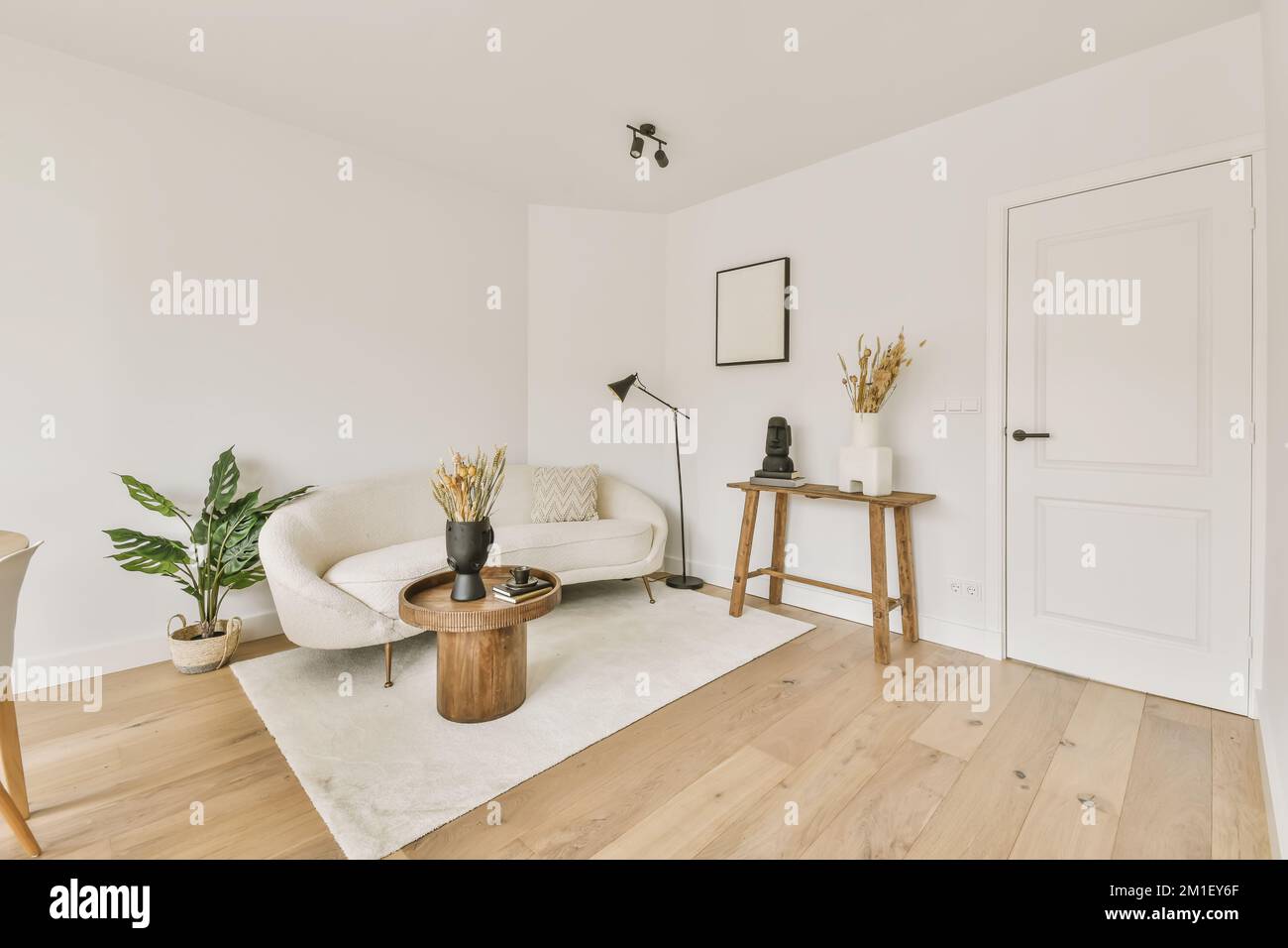 soggiorno con pareti bianche e pavimenti in legno massello la camera è decorata in tonalità neutre, tra cui pavimenti in legno chiaro Foto Stock