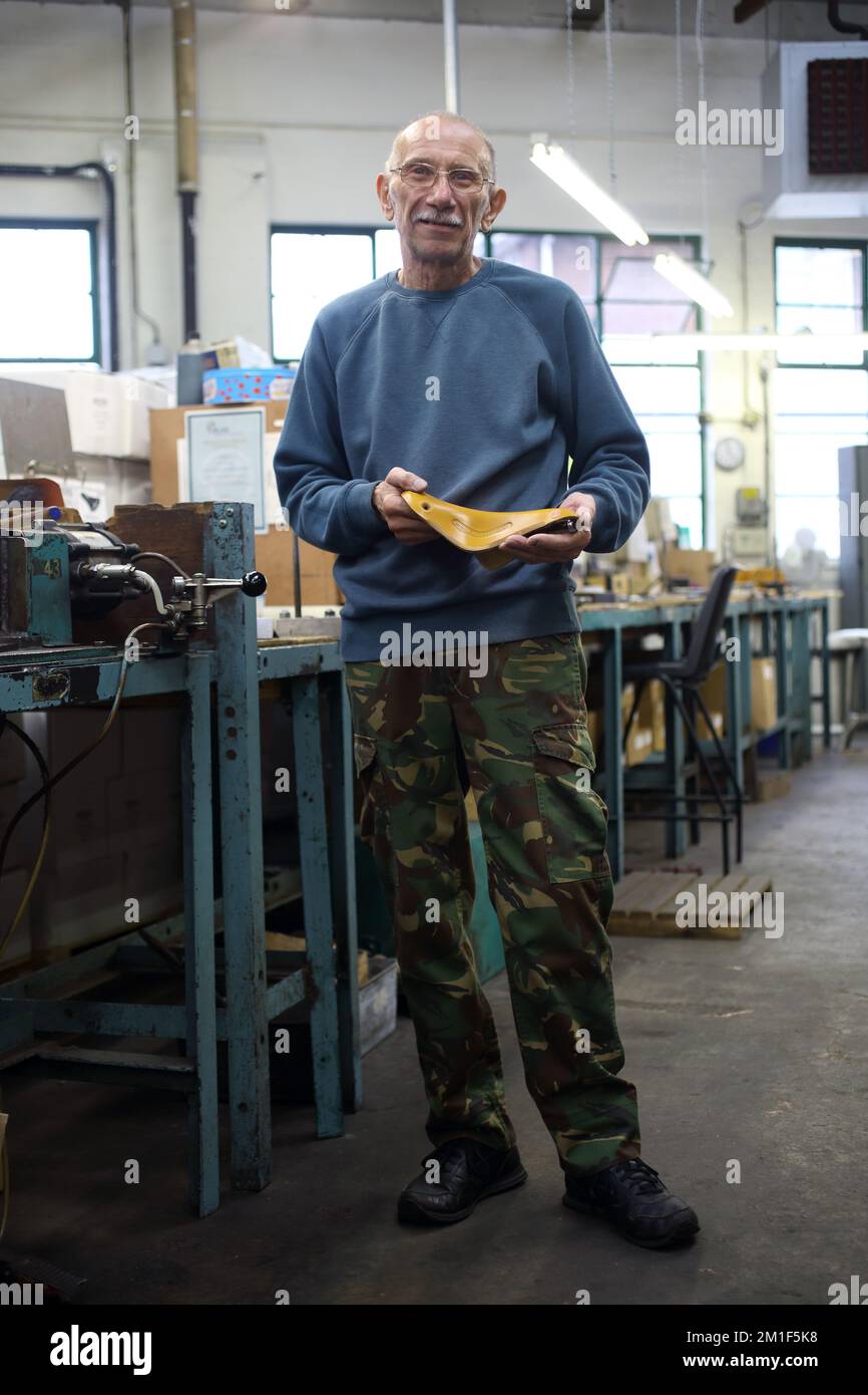 Lavoratore che tiene le selle Brooks alla fabbrica di sella Brooks a Birmingham, Regno Unito. Foto Stock