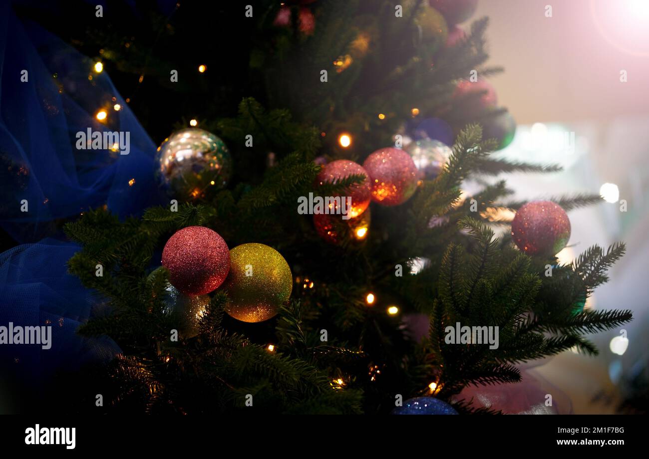 Decorazioni natalizie sull'albero delle feste. Palline colorate ghirlanda lampade incandescenti. Festivo sfondo tradizionale celebrazione per il nuovo anno Foto Stock