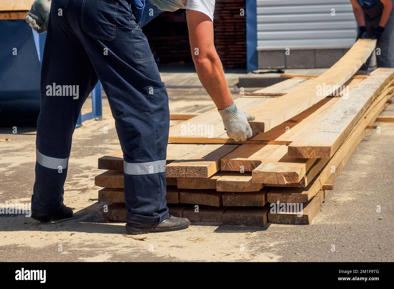 I lavoratori indossano tavole di legno in segheria o in Falegnameria. Flusso di lavoro autentico. Raccolta del legname per la costruzione. Carpentieri impilare le tavole. Background industriale.. Foto Stock