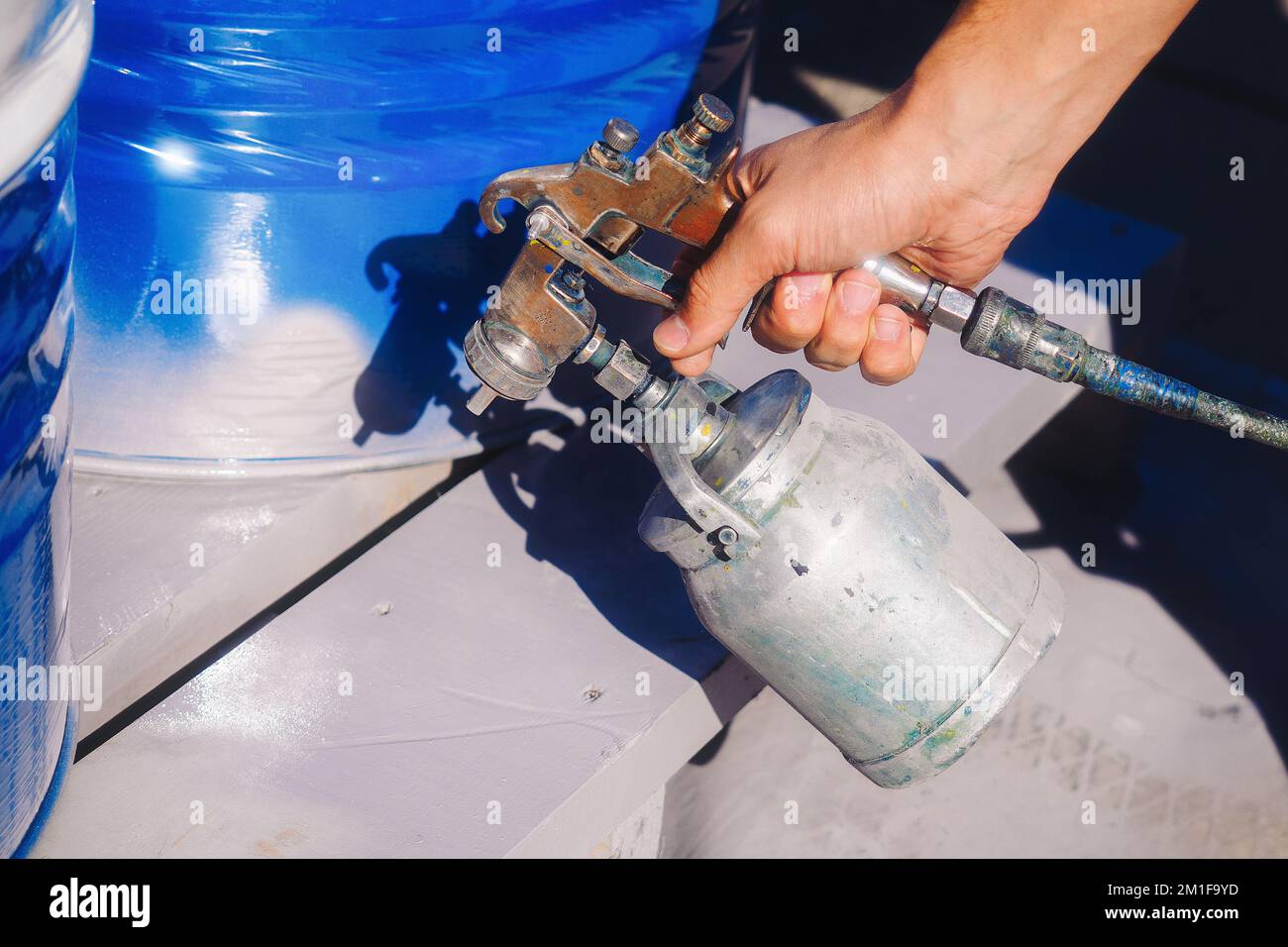 Pittura a mano con spruzzatore a pistola primo piano. Colorazione professionale. Sfondo. Foto Stock