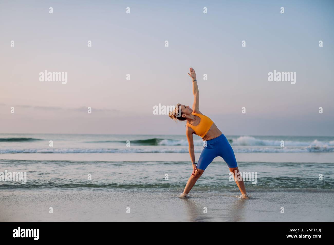 Giovane donna che fa esercizi in spiaggia, routine mattutina e concetto di stile di vita sano. Foto Stock