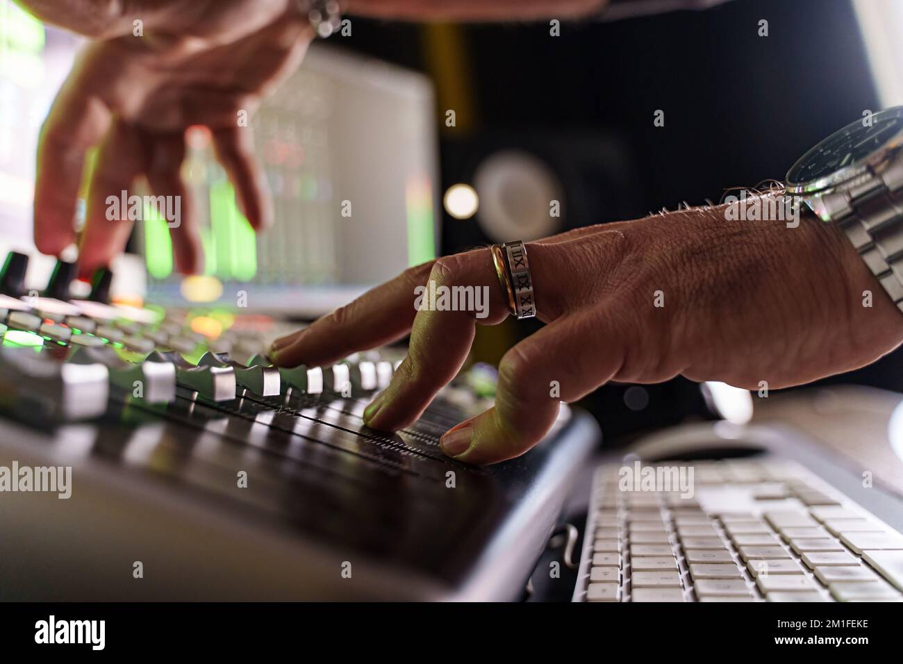 Primo piano del produttore di musica caucasica che affievolisce il volume sul pannello di controllo del mixer audio in un piccolo studio di produzione musicale - ingegnere audio al lavoro - musica e. Foto Stock