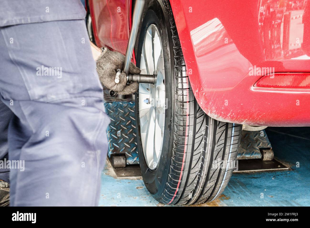 Servizio sostituzione pneumatici, meccanico con chiave funzionante in officina riparazione auto sostituzione ruote auto Foto Stock