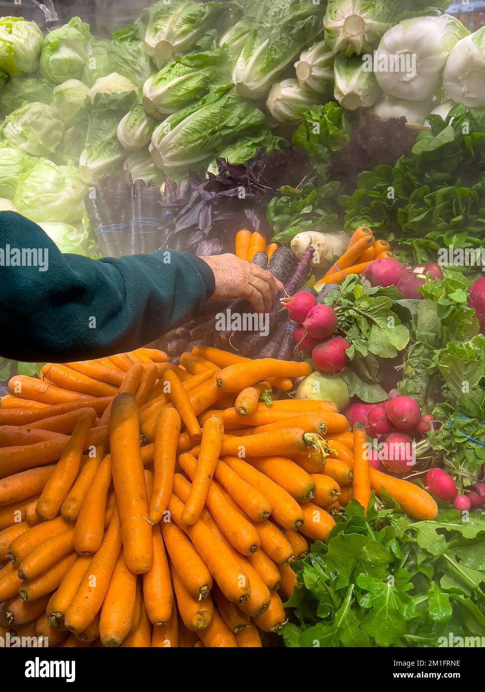 Un uomo nel mercato acquista verdure fresche per preparare cibo delizioso. Foto Stock