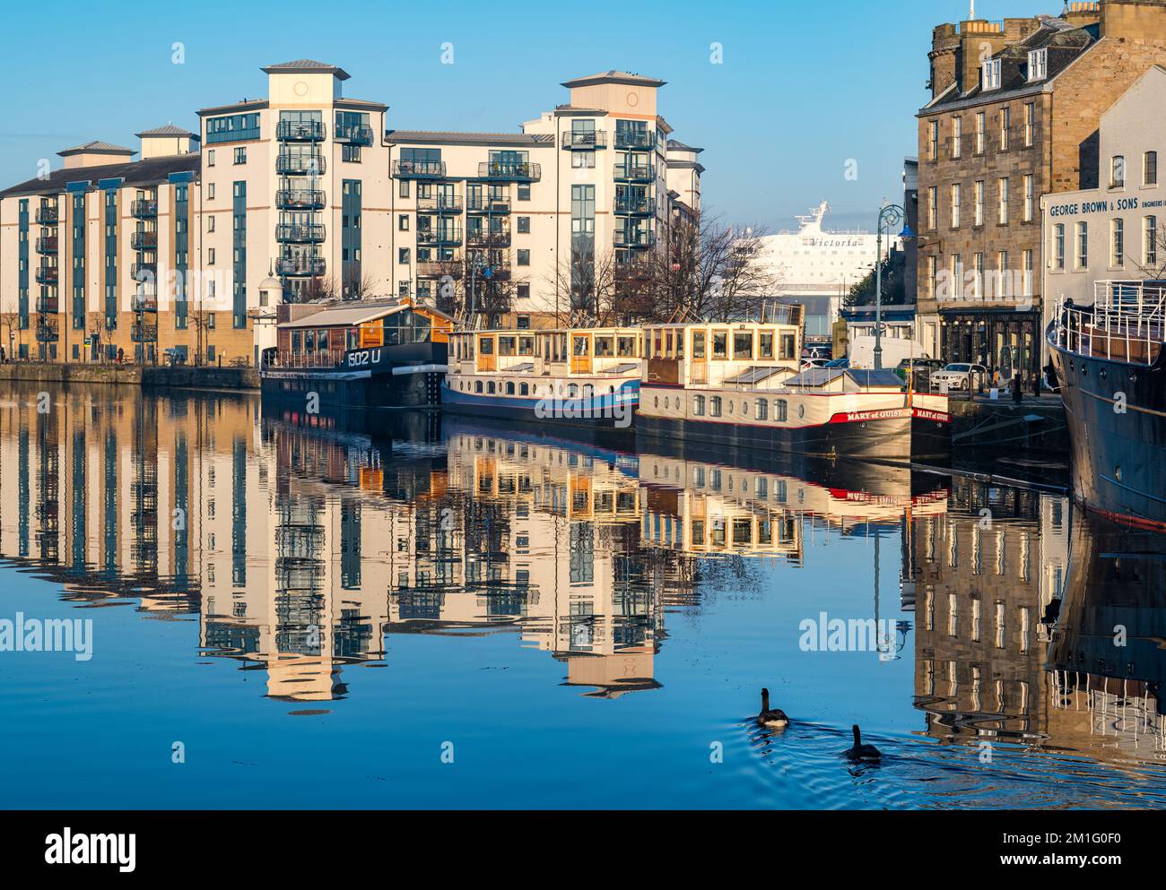 Riflessi soleggiati di barche sulla riva sulle acque del fiume Leith, Leith, Edimburgo, Scozia, Regno Unito Foto Stock
