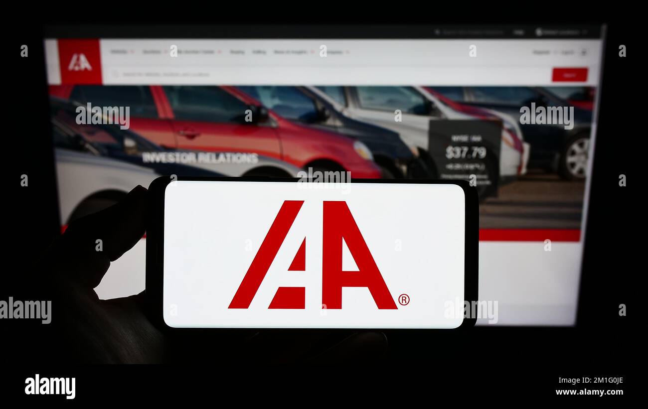 Persona in possesso di smartphone con il logo della società di mercato auto USA IAA Inc. Sullo schermo di fronte al sito Web. Messa a fuoco sul display del telefono. Foto Stock