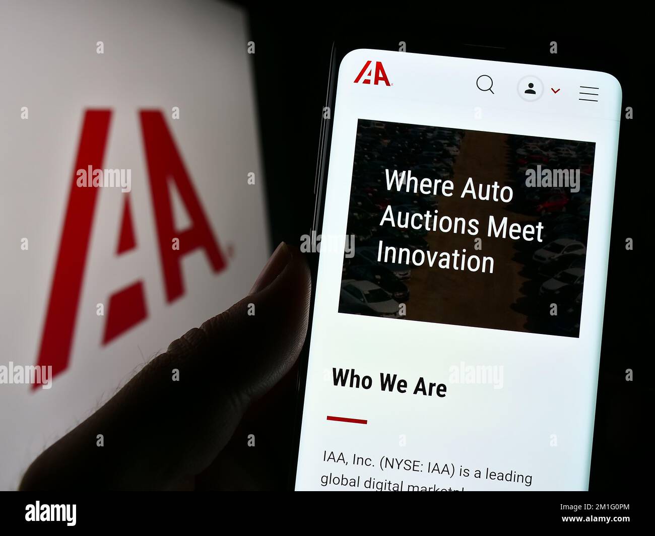 Persona in possesso di smartphone con pagina web della società di mercato auto USA IAA Inc. Sullo schermo di fronte al logo. Messa a fuoco al centro del display del telefono. Foto Stock