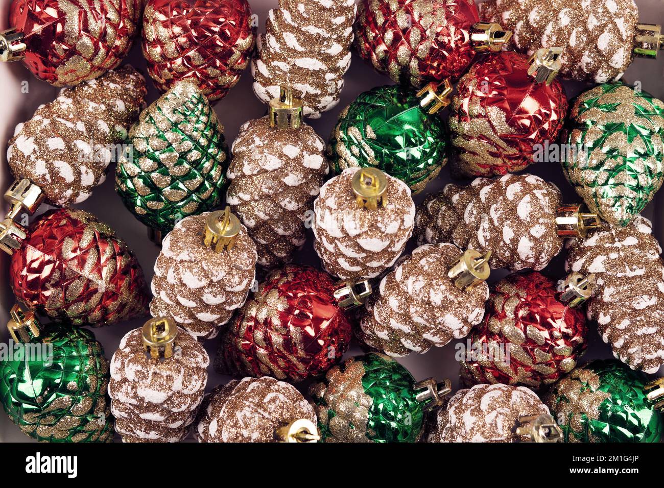 Sfondo astratto delle decorazioni natalizie in forma di coni di pino nei colori verde, rosso e oro. Buon Natale e Capodanno 2023 Foto Stock