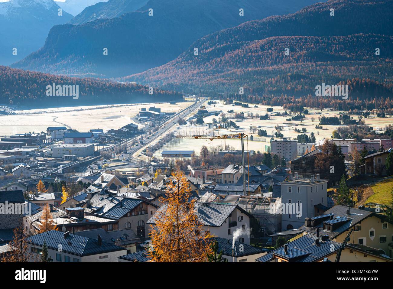 Paesaggio autunnale di montagne ricoperte di larici color oro e rime sul pavimento della valle Engadina vicino alla città di Samedan in Svizzera. Foto Stock