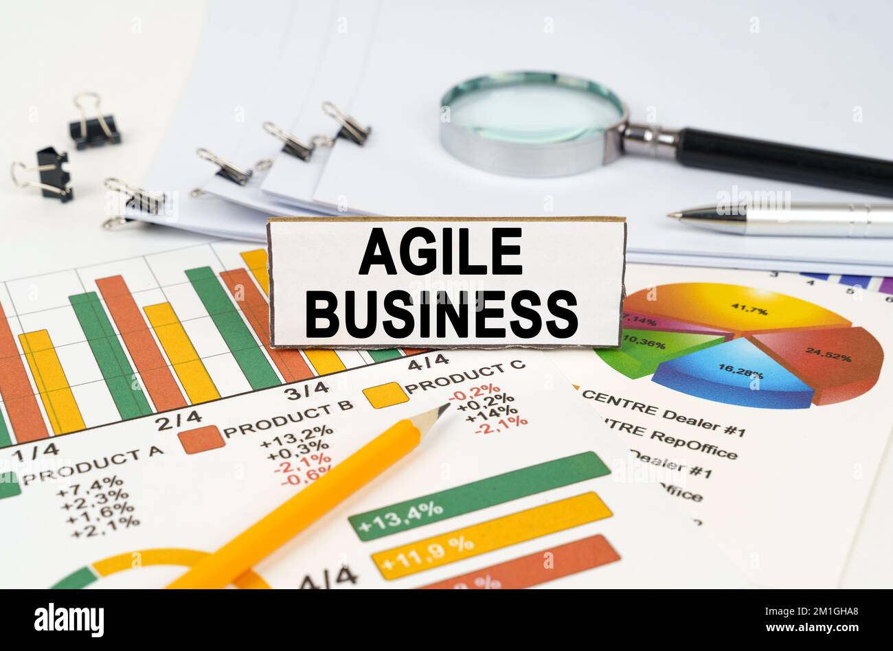 Concetto aziendale. Sui grafici di affari si trova una lente d'ingrandimento, una penna e un segno con l'iscrizione - Agile Business Foto Stock