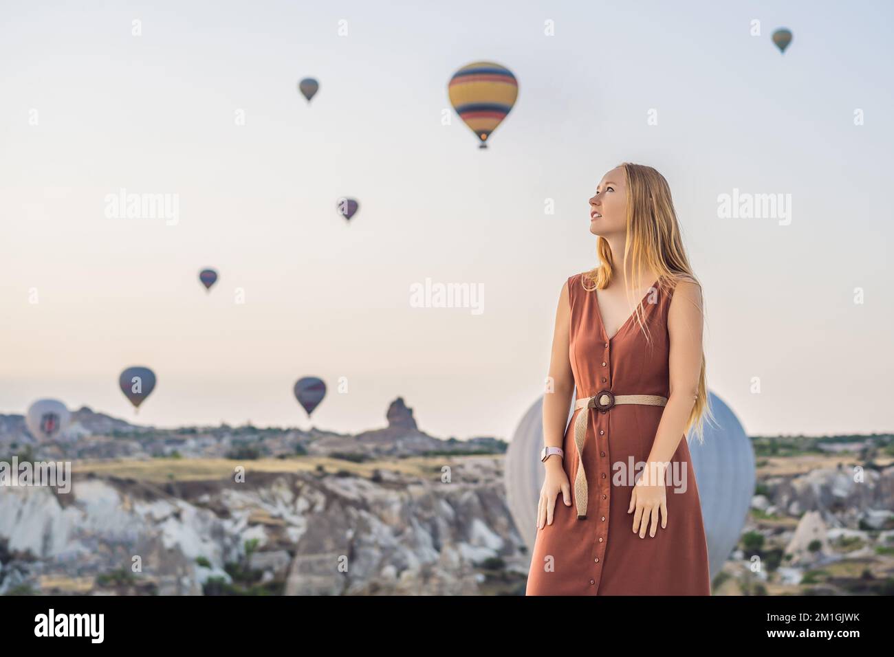 Donna turistica che guarda mongolfiere in Cappadocia, Turchia. Buon viaggio in Turchia concetto. Donna in cima a una montagna che gode di una vista meravigliosa Foto Stock