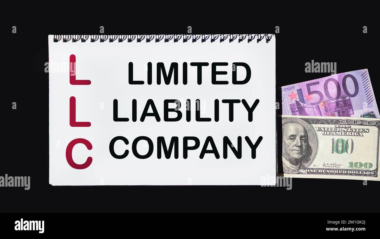 Concetto di business e finanza. Sul tavolo sono dollari, euro e un blocco note su cui è scritto - SOCIETÀ A RESPONSABILITÀ LIMITATA Foto Stock