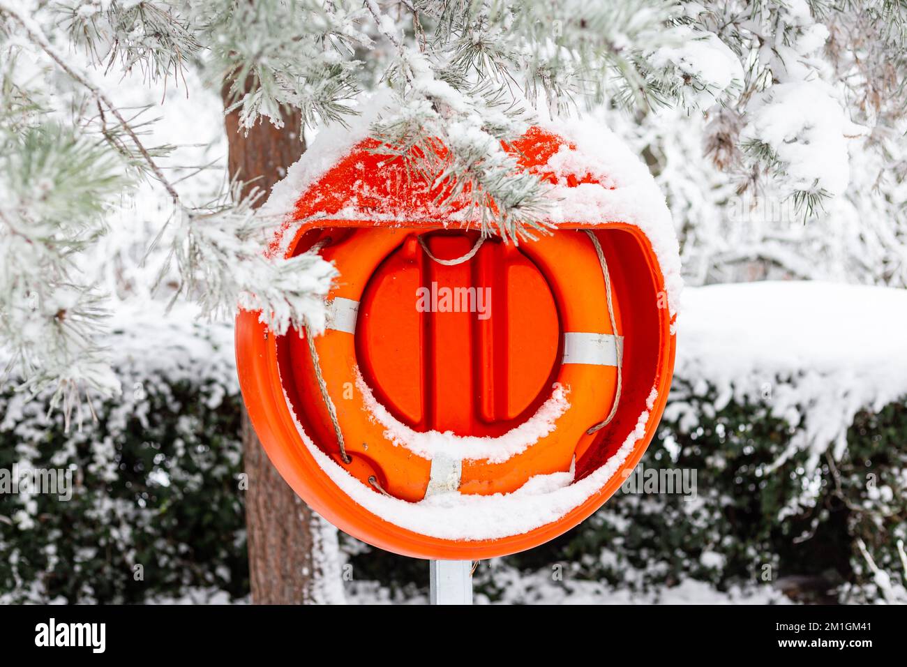 Lifebouy in neve fitta vicino allo stagno in Alexander Palace.Ready e di colore rosso brillante con accessibilità in caso di emergenza o un incidente Foto Stock