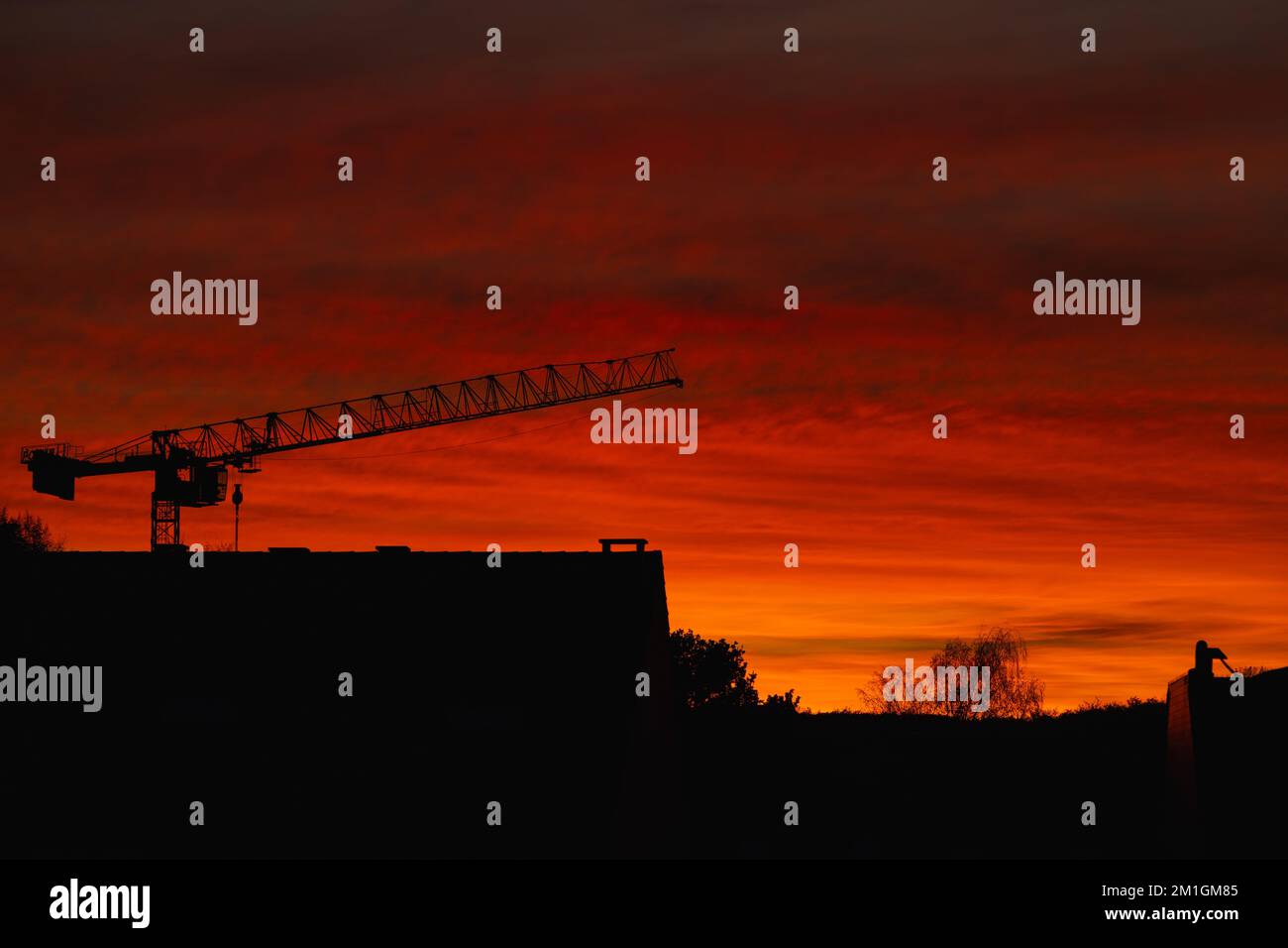 Tramonto rosso. Silhouette cittadina al tramonto. Silhouette della gru contro il cielo rosso Foto Stock