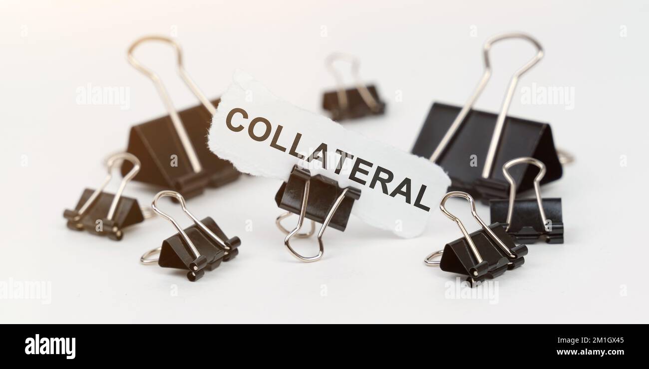 Concetto di business e finanza. Su un tavolo bianco ci sono dei morsetti da ufficio, in un clip c'è della carta con l'iscrizione - COLLATERALE Foto Stock