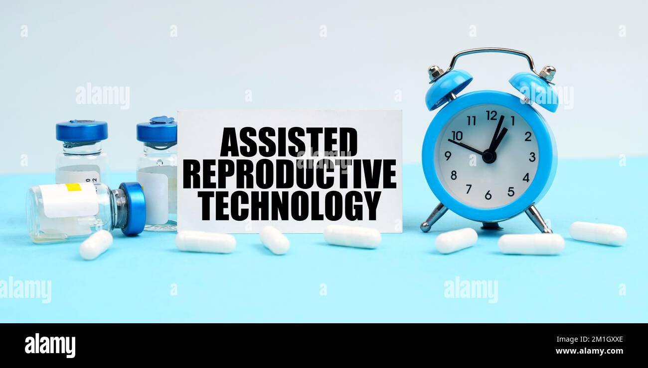 Medicina e concetto di salute. Un orologio di allarme, pillole, iniezioni e una scheda con l'iscrizione - Assisted Reproductive Technology Foto Stock