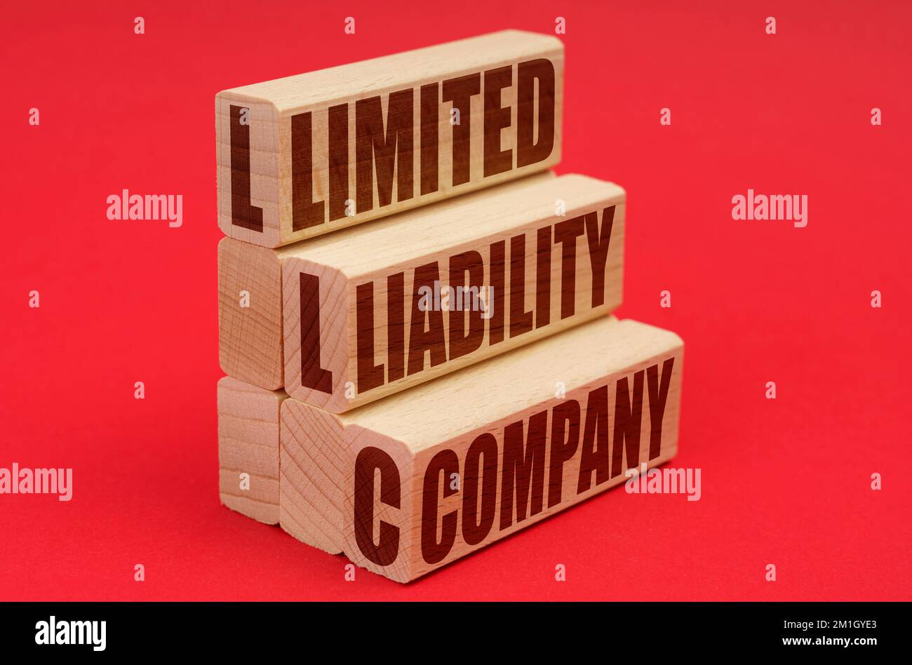 Business e concetto di economia. Su sfondo rosso, blocchi di legno con l'iscrizione - Limited Liability Company Foto Stock