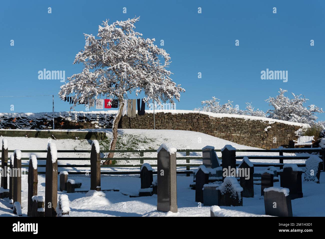 Presa a Rossendale Lancashire il 11 dicembre 2022. Pietre di tomba nel cortile con lavaggio appeso ad una linea di lavaggio. Neve a terra. Foto Stock