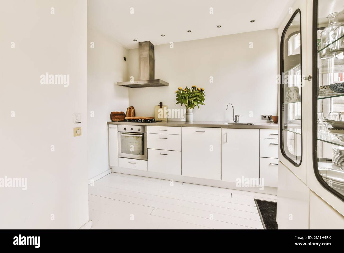 una cucina con armadietti bianchi e countertops neri sulla parete in uno spazio aperto piano che è ben organizzato Foto Stock