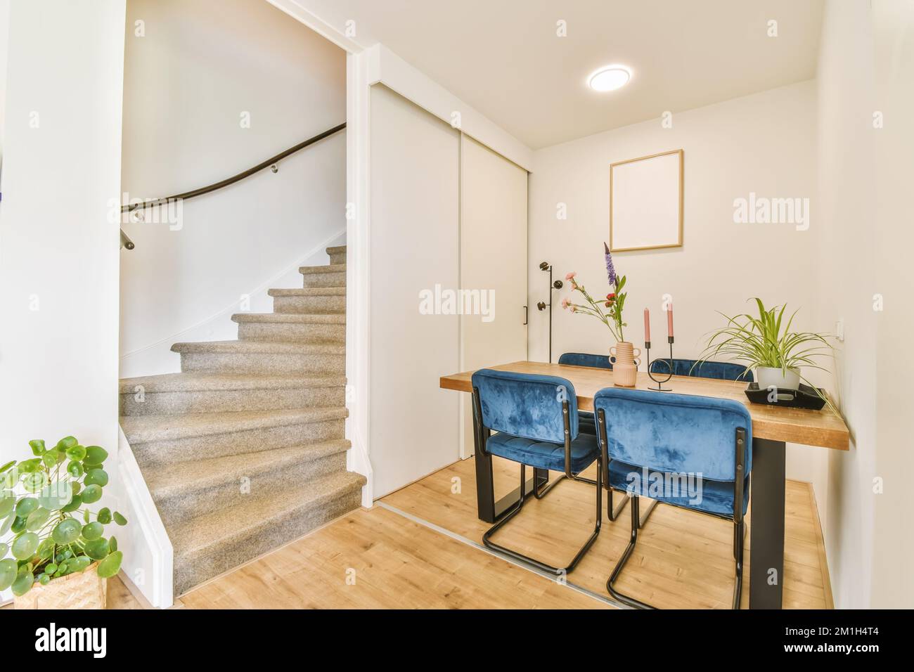 un soggiorno con due sedie blu e un tavolo di legno davanti alla scala che  porta al secondo piano Foto stock - Alamy