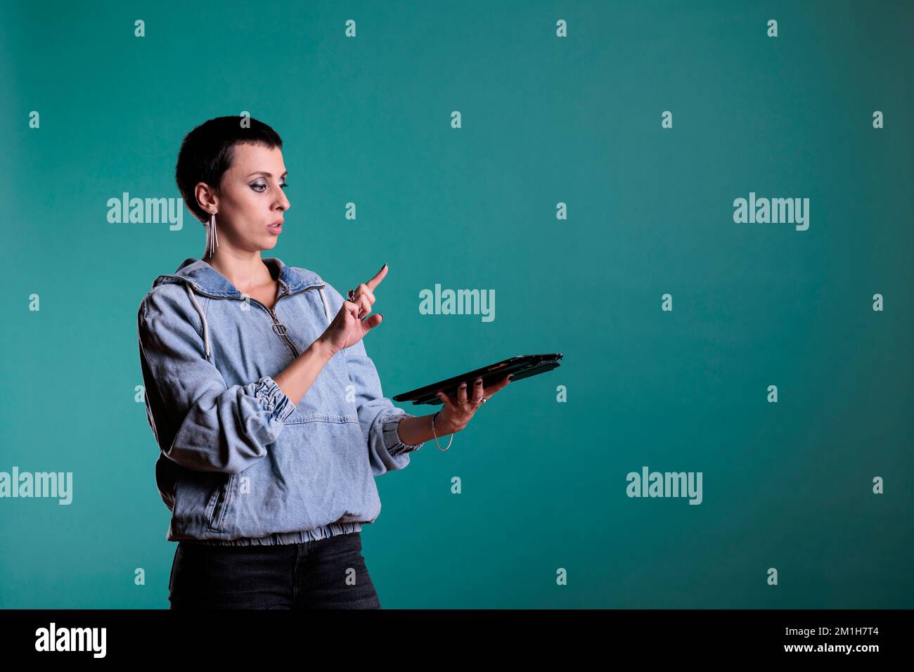 Donna Cheful che tiene un computer tablet utilizzando un'interfaccia di database olografica con realtà aumentata, in piedi in studio con sfondo isolato. Donna con esperienza futuristica utilizzando la tecnologia. Foto Stock