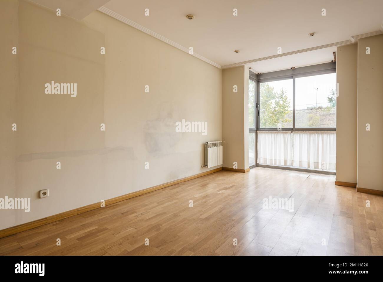 Una stanza vuota con pareti piene di segni dai vecchi mobili e una finestra a bovindo con tende in basso Foto Stock