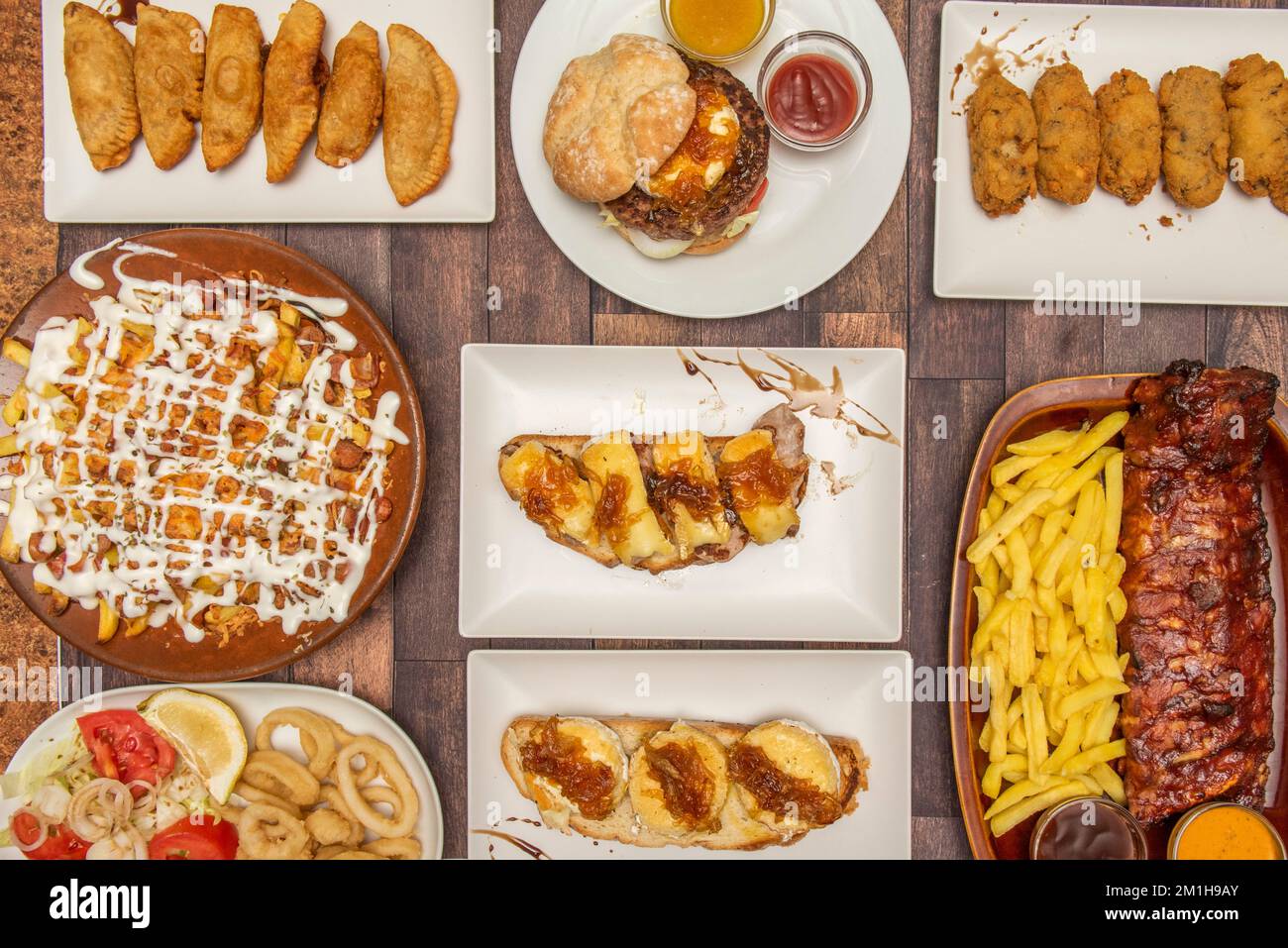 Piatti spagnoli e tapas set, formaggio di capra e toast di cipolla, calamari fritti, costolette arrosto, crocchette di prosciutto fatto in casa e empanadas di bonito Foto Stock