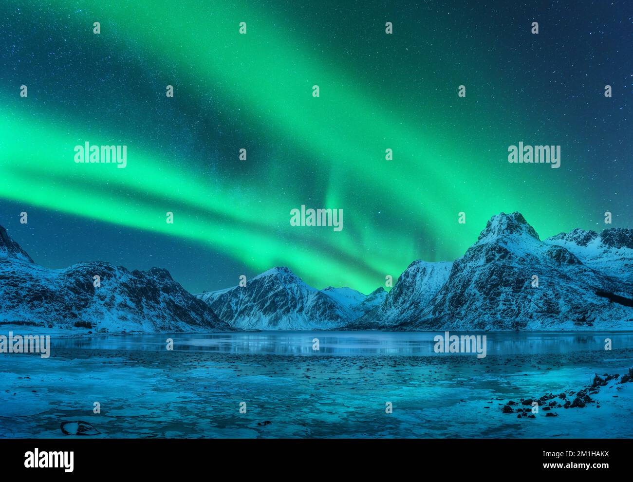 Aurora borealis su montagne innevate, costa di mare ghiacciata Foto Stock