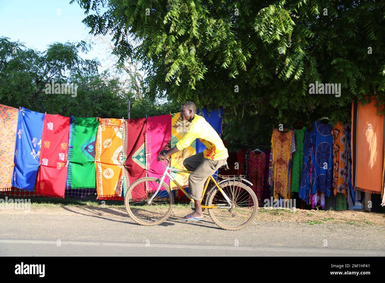 Un maschio in bicicletta su una strada di Ukunda Foto Stock