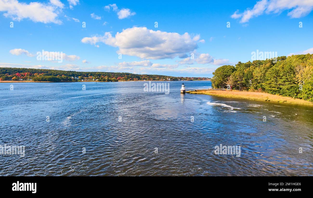 Vista in lontananza sul fiume di piccolo faro nel Maine con fogliame autunnale Foto Stock