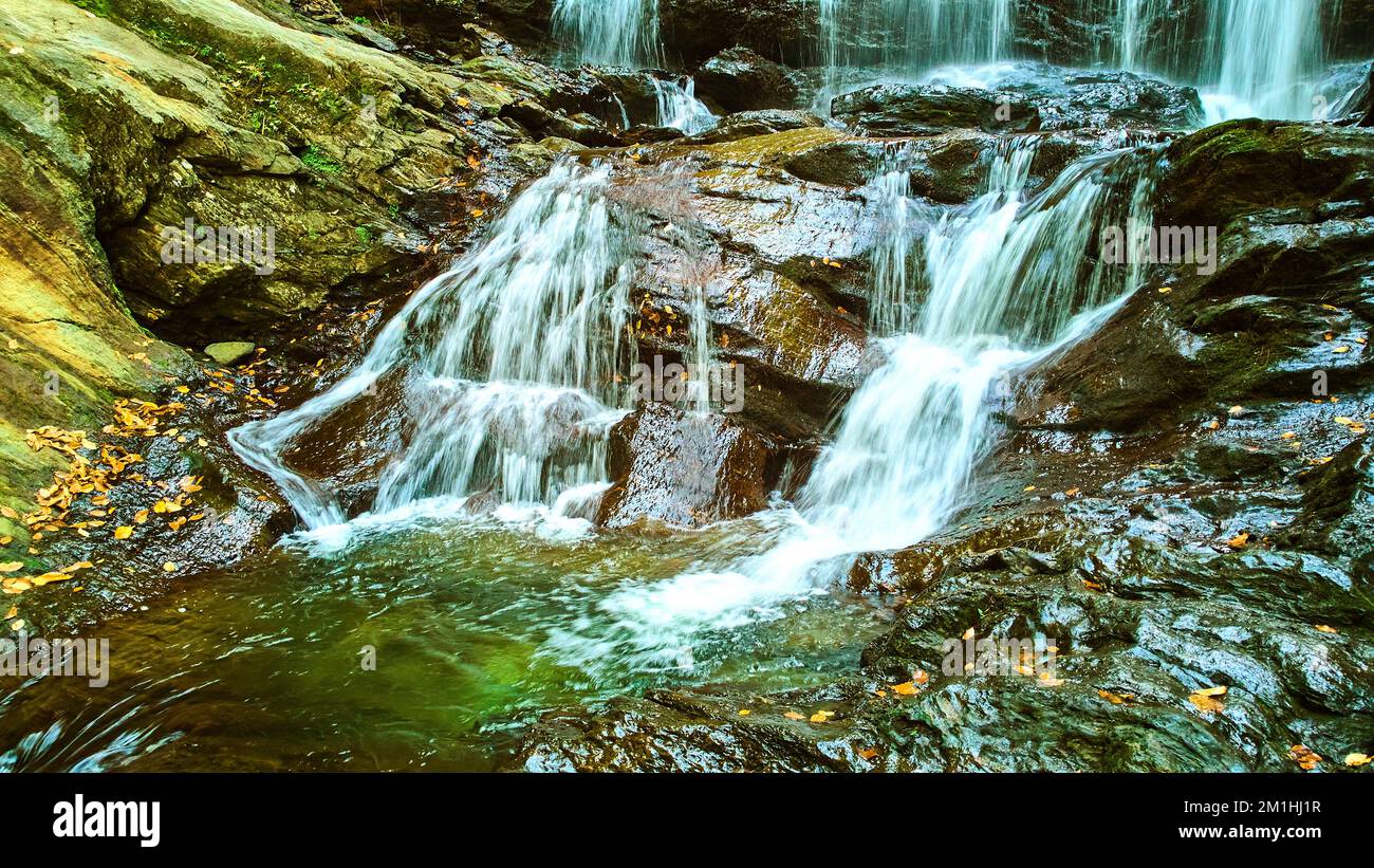 Particolare delle cascate inferiori che si scendono dolcemente sulla superficie rocciosa con foglie di caduta Foto Stock
