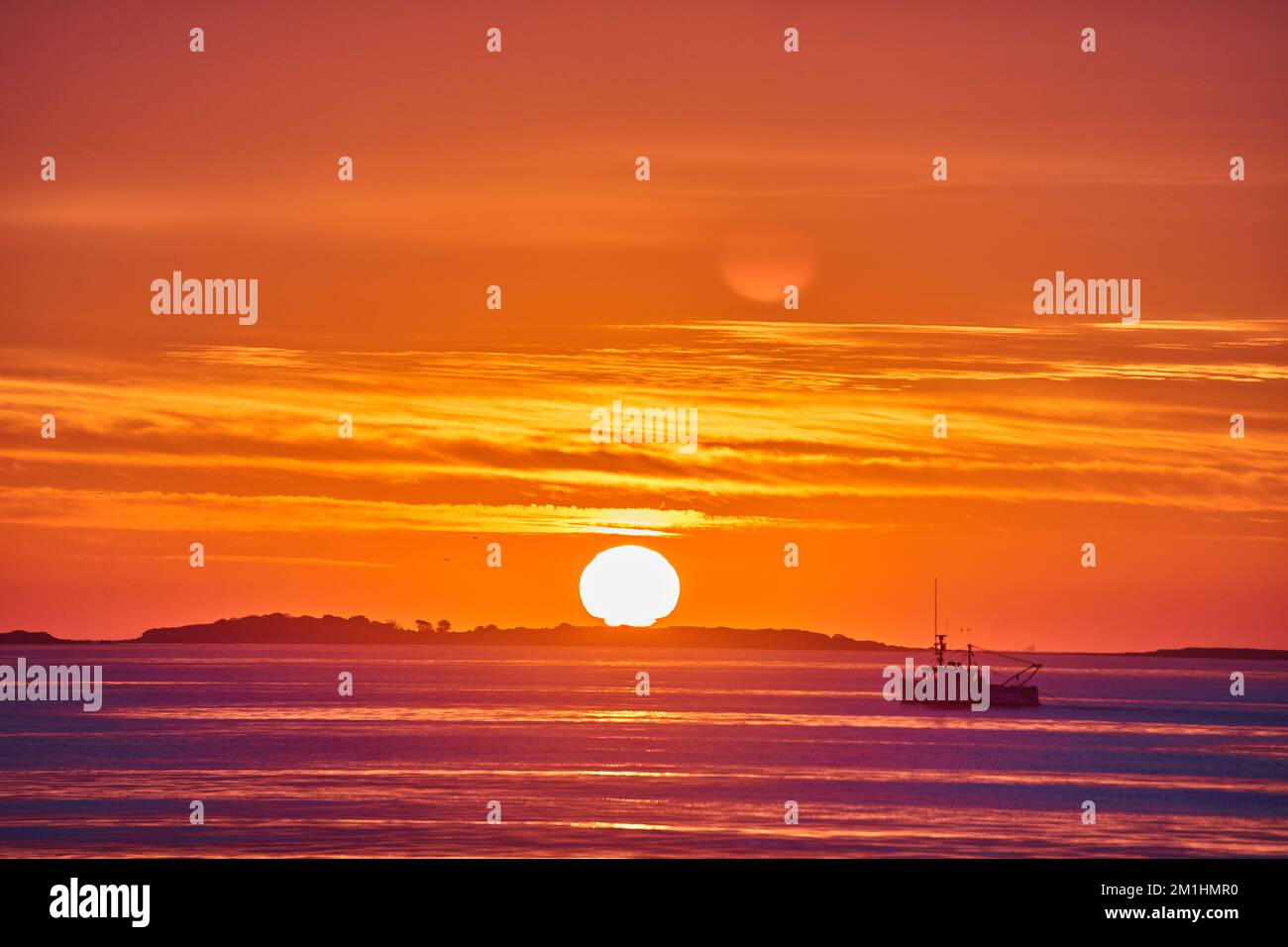 Incredibile alba particolare di sole e costa oceanica con nave da pesca e luce dorata Foto Stock